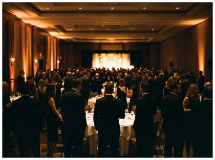 Guests in cocktail attire at a corporate holiday gala in a warmly lit hotel ballroom